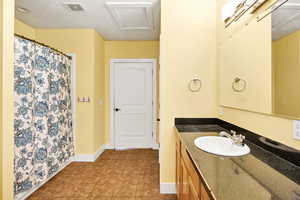 Full primary bathroom featuring vanity, tile flooring, a cultured marble shower with shower curtain, and a textured ceiling