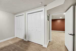 Unfurnished bedroom featuring carpet flooring, a textured ceiling, and two closets