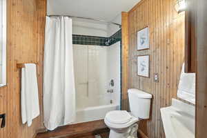Bathroom with wood walls and shower / bathtub combination with curtain