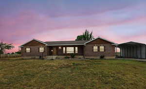 Single story home featuring a detached carport, a porch, a lawn, and brick siding