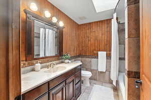 Full bathroom with vanity, tile patterned flooring, tile walls, a wainscoted wall, and shower / bath combo with shower curtain
