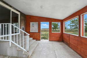Unfurnished sunroom with vaulted ceiling and wooden walls