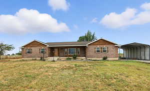 Single story home featuring a carport, brick siding, a porch, and a front lawn
