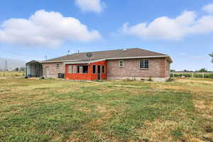 Back of house with brick siding, a carport, and a lawn