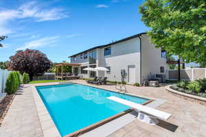 View of swimming pool featuring a hot tub, a patio area, a pergola, a diving board, and a fenced backyard