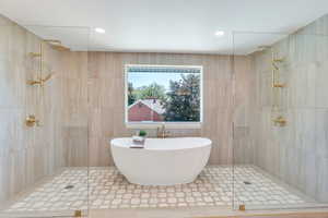 Bathroom featuring a tile shower, a freestanding bath, tile walls, and recessed lighting