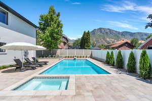 View of swimming pool with a fenced backyard, a patio area, an in-ground hot tub, and a mountain view