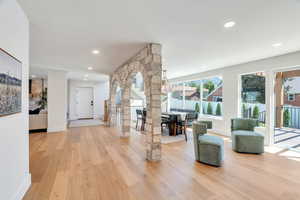 Living room with light wood-type flooring, decorative columns, and recessed lighting