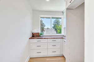 Interior space featuring wooden counters, white cabinets, and light wood-type flooring