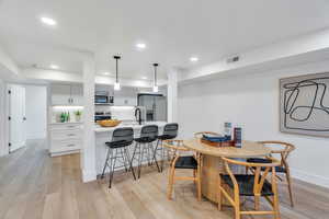 Dining space with light wood finished floors and recessed lighting