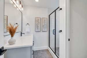 Bathroom with double vanity, a shower stall, and recessed lighting