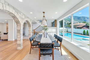 Dining space featuring a mountain view, light wood-type flooring, arched walkways, recessed lighting, and stairs