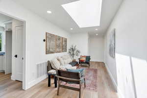 Sitting room with a skylight, light wood-style floors, and recessed lighting