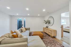 Living area with light wood-type flooring and recessed lighting