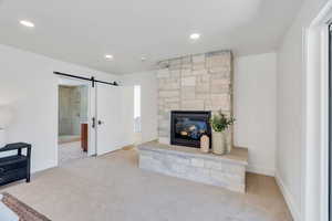 Unfurnished living room featuring a barn door, carpet flooring, recessed lighting, and a fireplace