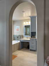 Full bathroom featuring a textured ceiling, a garden tub, and custom build vanity.