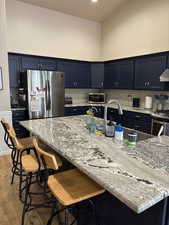 Kitchen with appliances with stainless steel finishes, a kitchen breakfast bar, light stone countertops, tasteful backsplash.