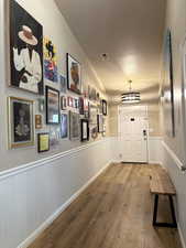 Hallway featuring a textured ceiling, a wainscoted wall, and lofted ceiling
