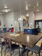 Dining space featuring vaulted ceiling, LVP floors, arched walkways, and recessed lighting