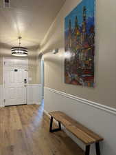Hall with a wainscoted wall, arched walkways, and a chandelier