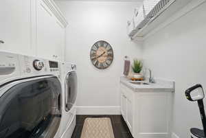 Washroom featuring washing machine and clothes dryer, cabinet space, and dark wood finished floors