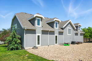 Rear view of property featuring stucco siding, roof with shingles, and a lawn