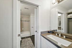 Bathroom featuring tile patterned flooring, vanity, and bathtub / shower combination