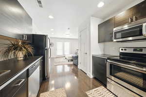 Kitchen featuring stainless steel appliances, recessed lighting, dark wood-style flooring, modern cabinets, and dark countertops