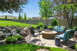 Fenced backyard featuring a patio area, an outdoor living space with a fire pit, and a mountain view