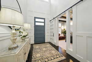 Foyer featuring a barn door, a decorative wall, a high ceiling, and wood tiled floors