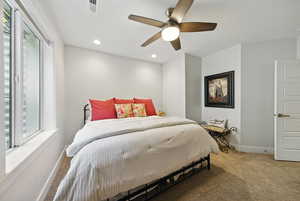 Carpeted bedroom with multiple windows, recessed lighting, and ceiling fan