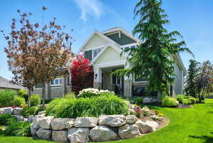 Craftsman inspired home with stone siding and a front lawn