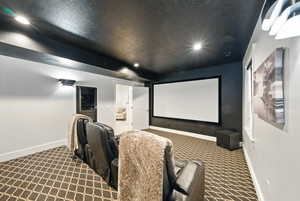 Cinema room featuring a textured ceiling, dark carpet, and recessed lighting