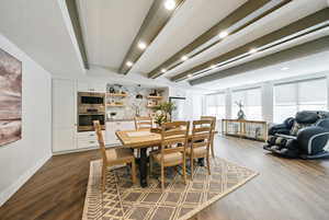 Dining space with dark wood-style flooring, beam ceiling, and recessed lighting