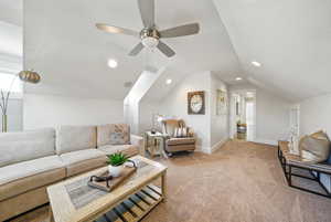 Carpeted living room featuring a ceiling fan, vaulted ceiling, and recessed lighting