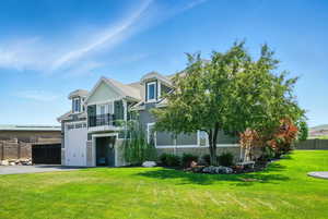 View of front of house featuring stone siding, a balcony, driveway, and an attached garage