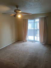 Carpeted empty room featuring ceiling fan and a textured ceiling