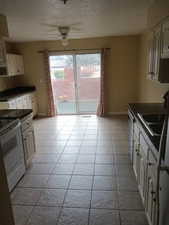 Kitchen featuring dark countertops, ceiling fan, white electric range oven, a textured ceiling, and dishwashing machine