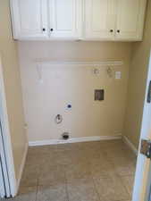 Washroom with hookup for a gas dryer, hookup for an electric dryer, cabinet space, and light tile patterned floors