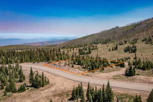 Aerial view of property and surrounding area with property parcel outlined and a mountainous background