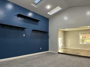 Carpeted empty room with a skylight and high vaulted ceiling