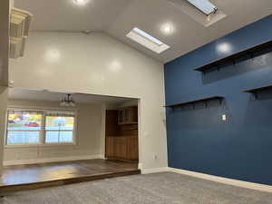 Carpeted living room with a skylight and high vaulted ceilings