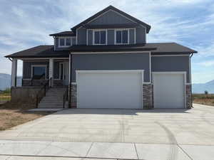 View of front of home with stone siding, concrete driveway, a garage, a mountain view, and a porch