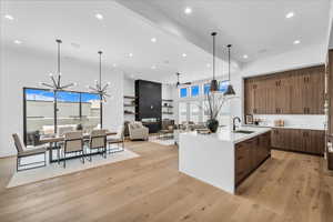 Kitchen featuring modern cabinets, light wood-style flooring, light countertops, an island with sink, and a chandelier