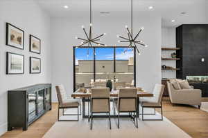 Dining room with light wood-style flooring, a chandelier, a towering ceiling, and recessed lighting