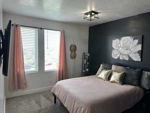 Carpeted bedroom featuring a textured ceiling and baseboards