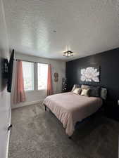 Bedroom with dark carpet and a textured ceiling