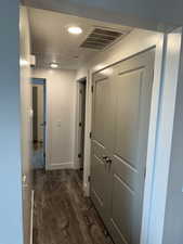 Corridor featuring a textured ceiling, wood finished floors, and recessed lighting