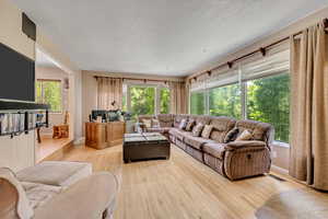 Living area with light wood-type flooring and a textured ceiling