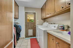 Laundry area with separate washer and dryer, cabinet space, and light tile patterned floors